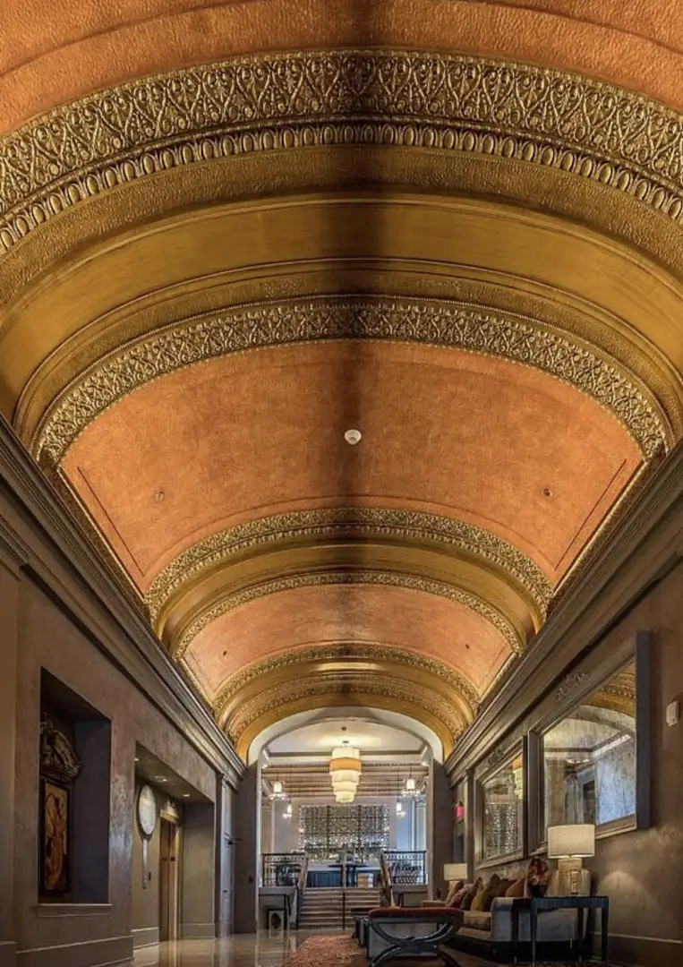 A hallway with a coffered ceiling and marble floor.