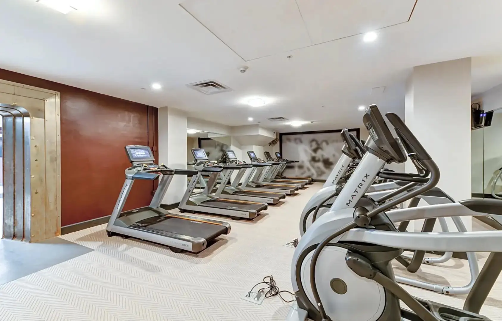 A fitness center with treadmills and elliptical machines.